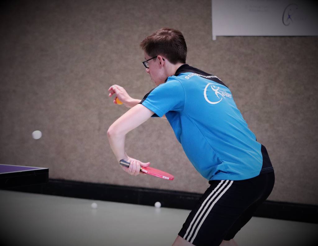 Sportunterricht im Tischtennis mit einem jungen Spieler, der eine schnelle Reaktion zeigt, um den Ball zu treffen. Perfekt für Training und Wettkämpfe im Tischtennis.