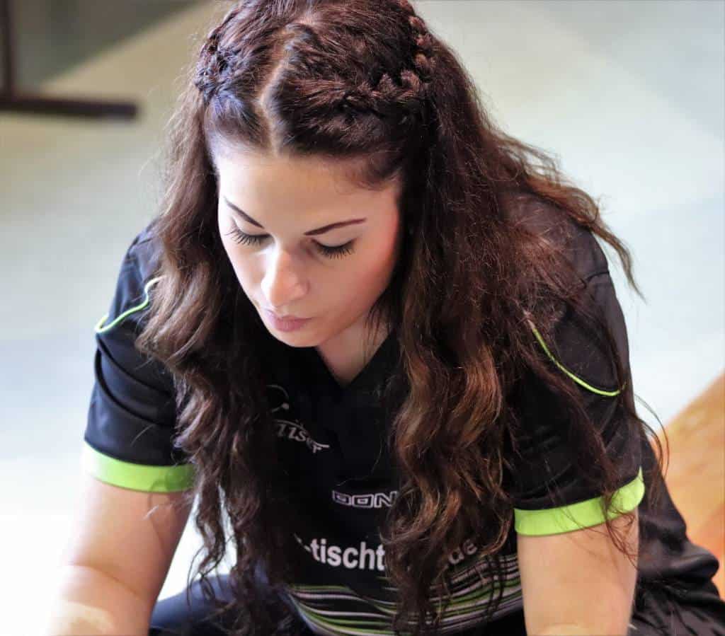 Motivierende Tischtennisspielerin in Sportjersey, konzentriert auf das Spiel, zeigt Leidenschaft und Engagement im Tischtennis-Training, ideal für Sport- und Tischtennis-Webseiten.
