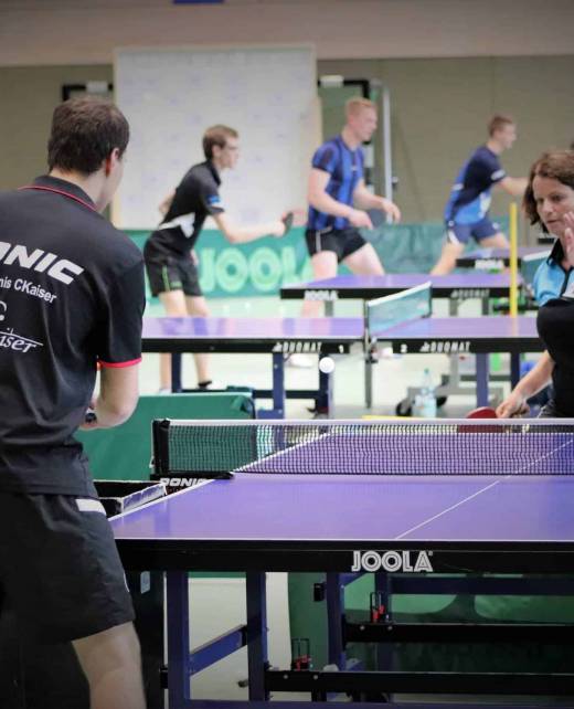 IMG_4242 Praktisches Tischtennisspiel in der Turnhalle, Trainerin gibt Anweisungen, Jugendliche trainieren in einer modernen Sporthalle.